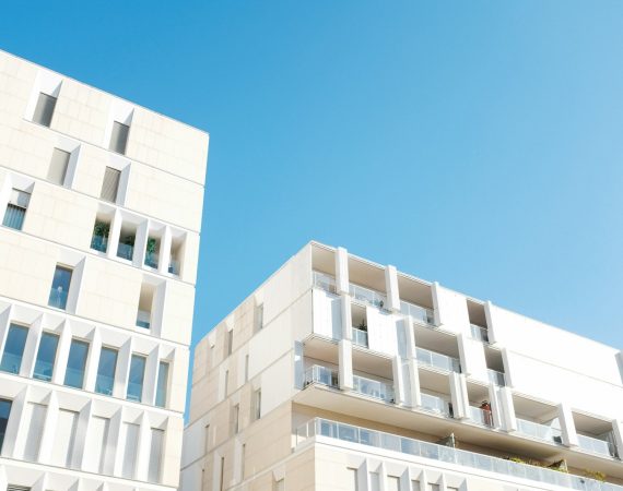 Modern white buildings with large windows against a clear blue sky, showcasing contemporary architecture