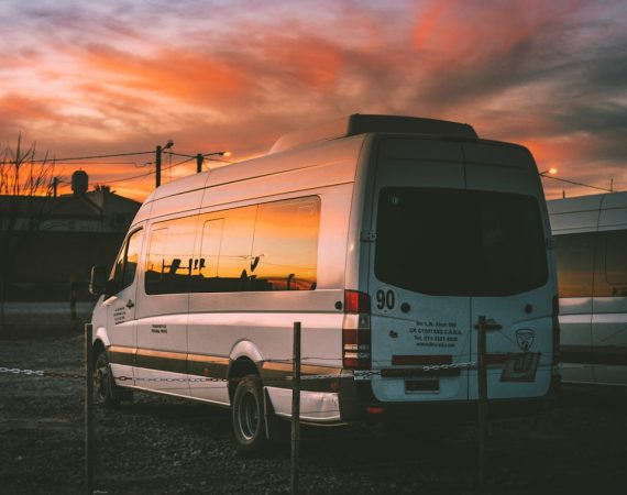 white Mercedes-Benz Sprinter parked on open yard beside chain rail
