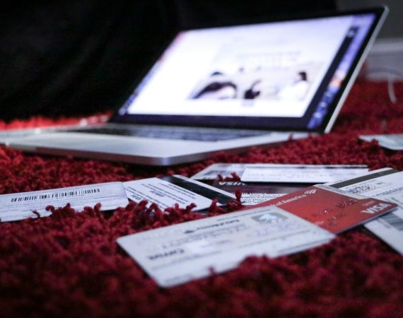 Scattered credit cards on red carpet in front of open laptop, highlighting online banking and finance security concerns