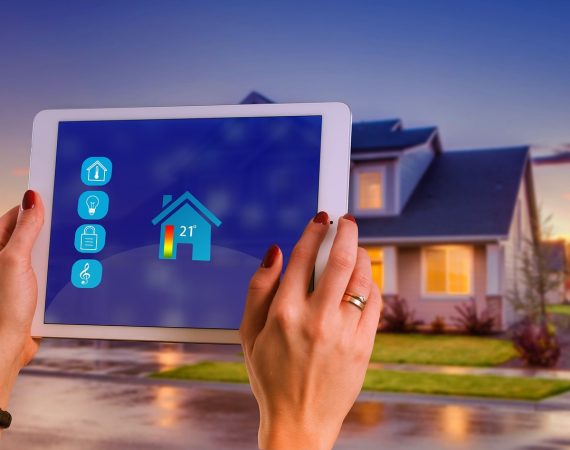 Person using tablet to control smart home temperature and security settings with modern house in background
