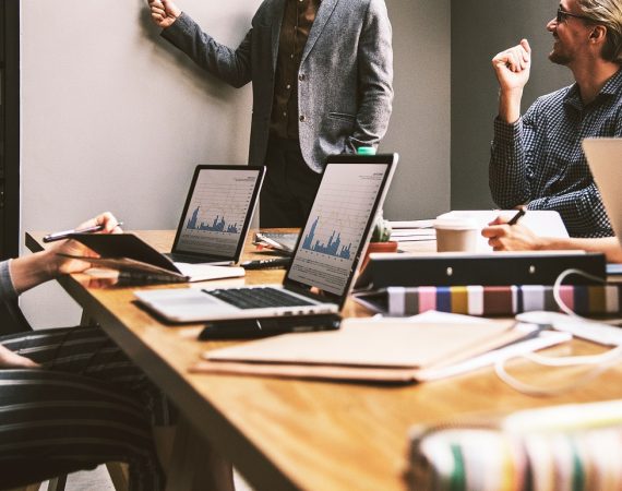 Team meeting with laptops showing graphs, colleagues engaged in discussion at a conference table