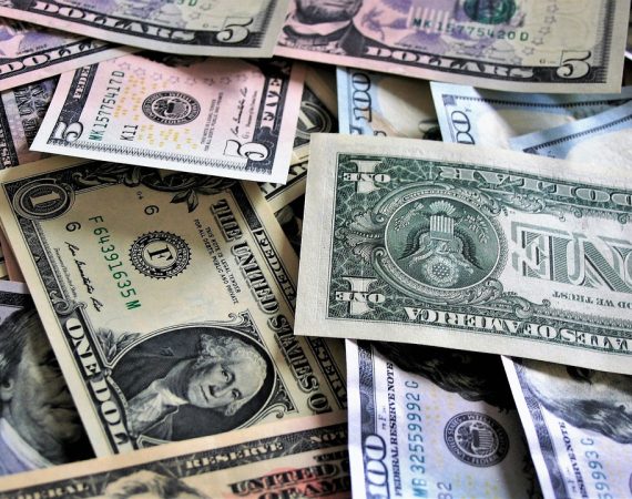 Assorted US dollar bills scattered in a pile, showcasing various denominations and designs