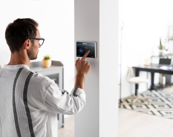 A man interacts with a smart home device app, focused on its screen in a modern living space