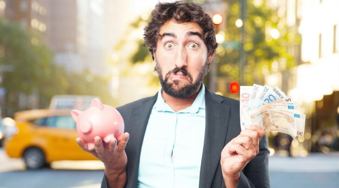 Man holding pink piggy bank and euro notes in city street, looking surprised