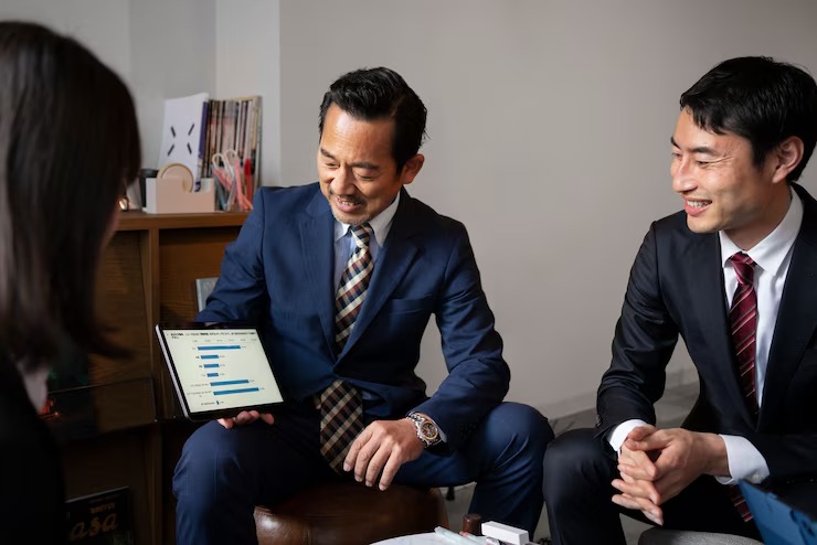 Business meeting with three professionals discussing data on a tablet, all dressed in suits, looking focused and engaged