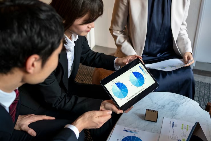 Business team analysing pie charts on a tablet during a meeting, discussing data insights and strategies