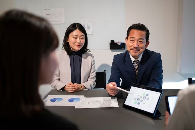 Business meeting with professionals discussing graphs and data on a tablet at a conference table