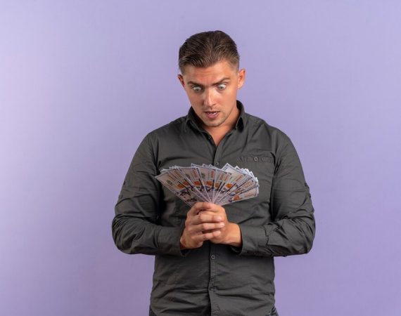 A man examines a fan he is holding, looking at it with curiosity
