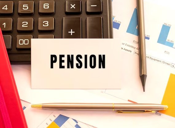 Pension calculator and a pen resting on a wooden desk, ready for financial planning