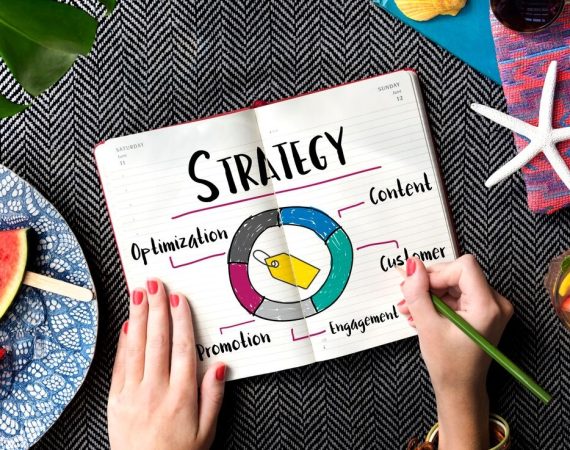 A close-up of a woman's hand gripping a notebook featuring a strategy diagram, illustrating thoughtful planning