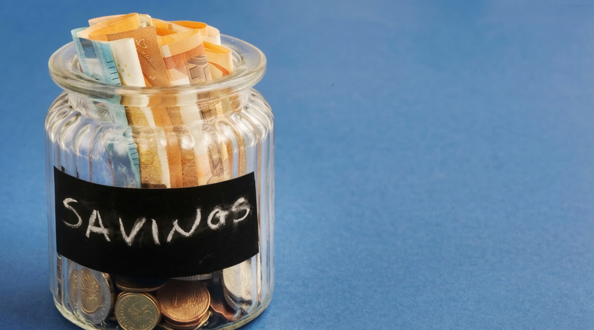 Jar filled with euro banknotes and coins labeled 'savings' on blue background